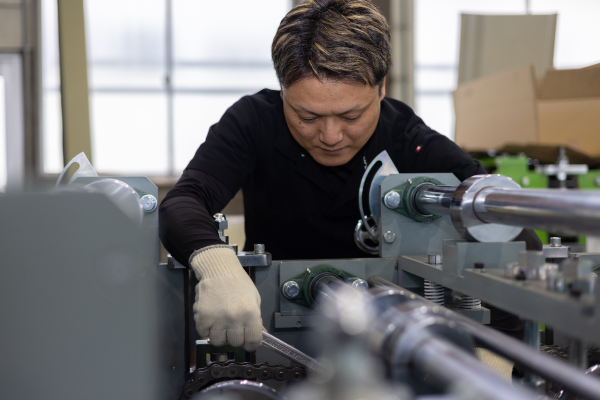 工具を使って機械の調整を行う菊地さん